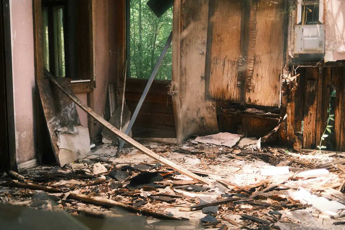 A fire-damaged room with charred walls and debris on the floor