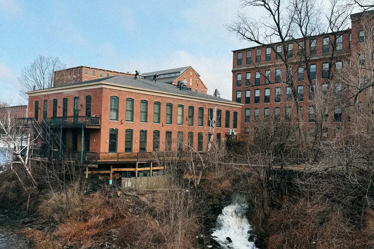 Old brick mill buildings beside a rushing river in New Hampshire